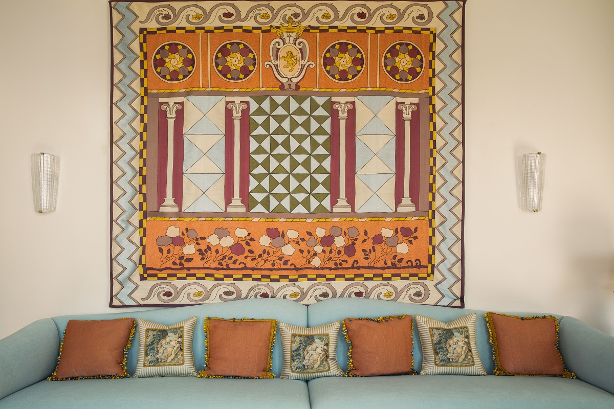 light blue couch with terracotta cushions and mural above in same colours in Villa Beatrice