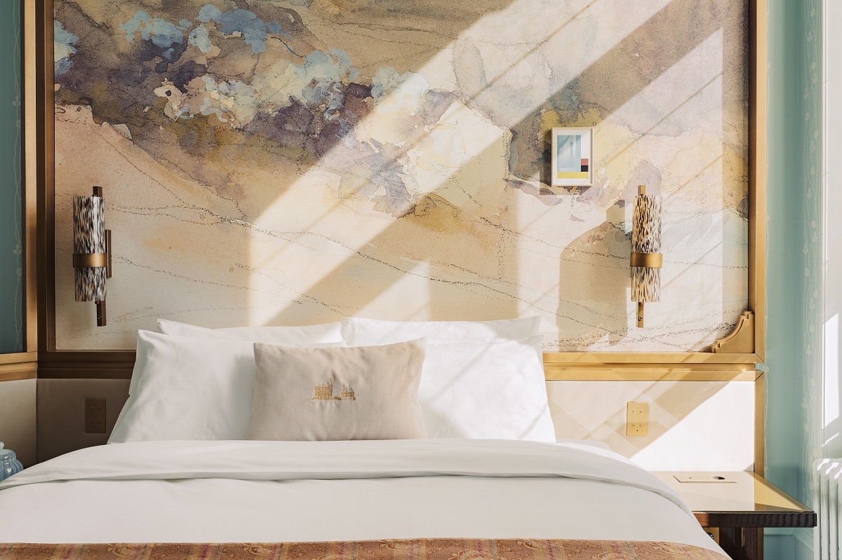 detail of bed in guestroom with sunlight on wallpaper 