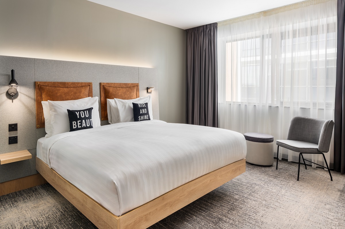 king bed with white linen , leather backrest pillow and patterned cushion on the bed