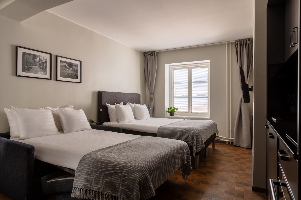 twin beds in Bob W Stockholm guestroom with white linen and grey throws