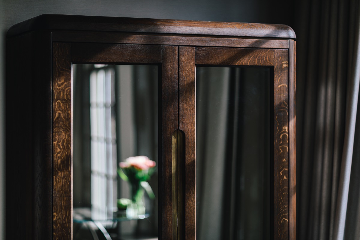 detail of wooden custom made cabinet in hotel suite with room reflected in the mirror