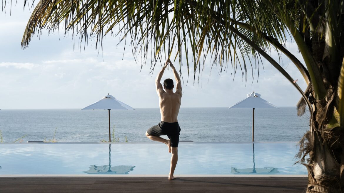 man in yoga pose next to palm tree and pool at Uga Prāva Sri Lanka