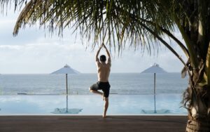 man in yoga pose next to palm tree and pool at Uga Prāva Sri Lanka