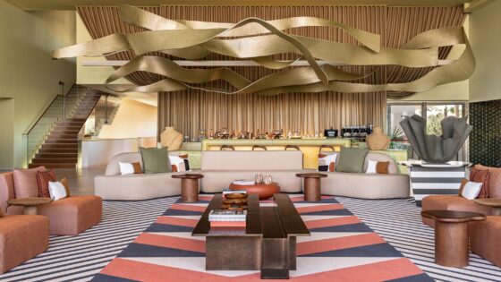 kimpton algarve lobby with orange and brown patterned carpet below gold sculptural ceiling installation
