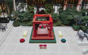 Raised on a platform and framed by bold red and green pillars, the ‘Day Bed’ structure feels at once playful and monumental. A fusion of sharp lines and organic shapes, the installation is industrial yet sumptuous. Low stools and benches in bright, Crayola hues are scattered across the tiled courtyard, inviting visitors to pause and take in the scene. With its bold palette of Plaza red and garden green, Uchronia has transformed the Hôtel Plaza Athénée courtyard space into a contemporary cubist exhibition, where – like a strange dream – a geometric bed awaits sleep outside, encased within the white walls of historic Paris.