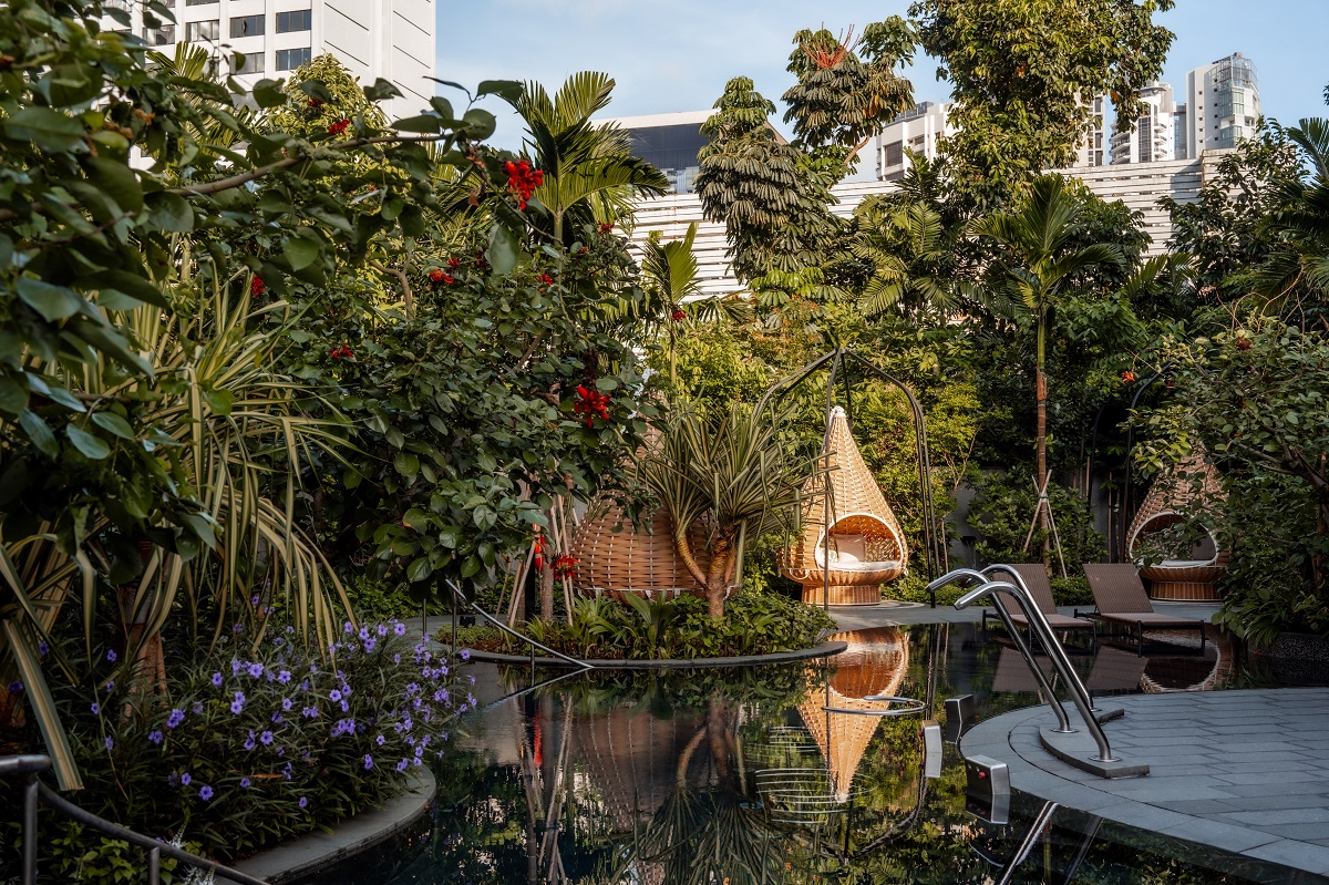 pools and pod cabanas in tropical garden with singapore skyline behind
