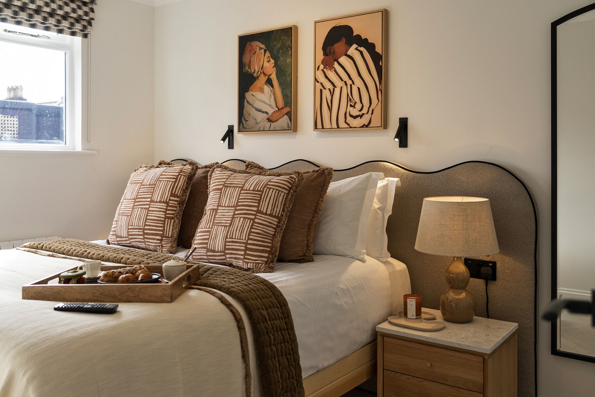 bed detail with scalloped headboard and paintings on the wall above