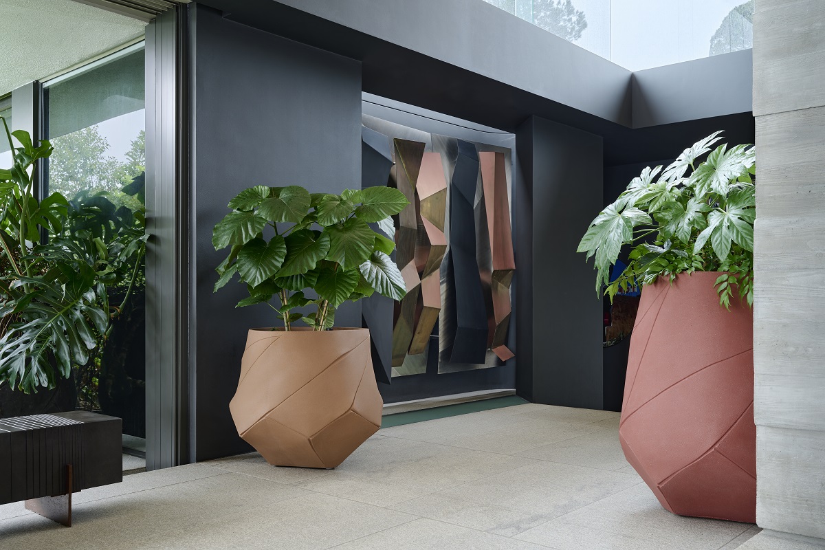 large faceted terracotta pots with plants against black walls