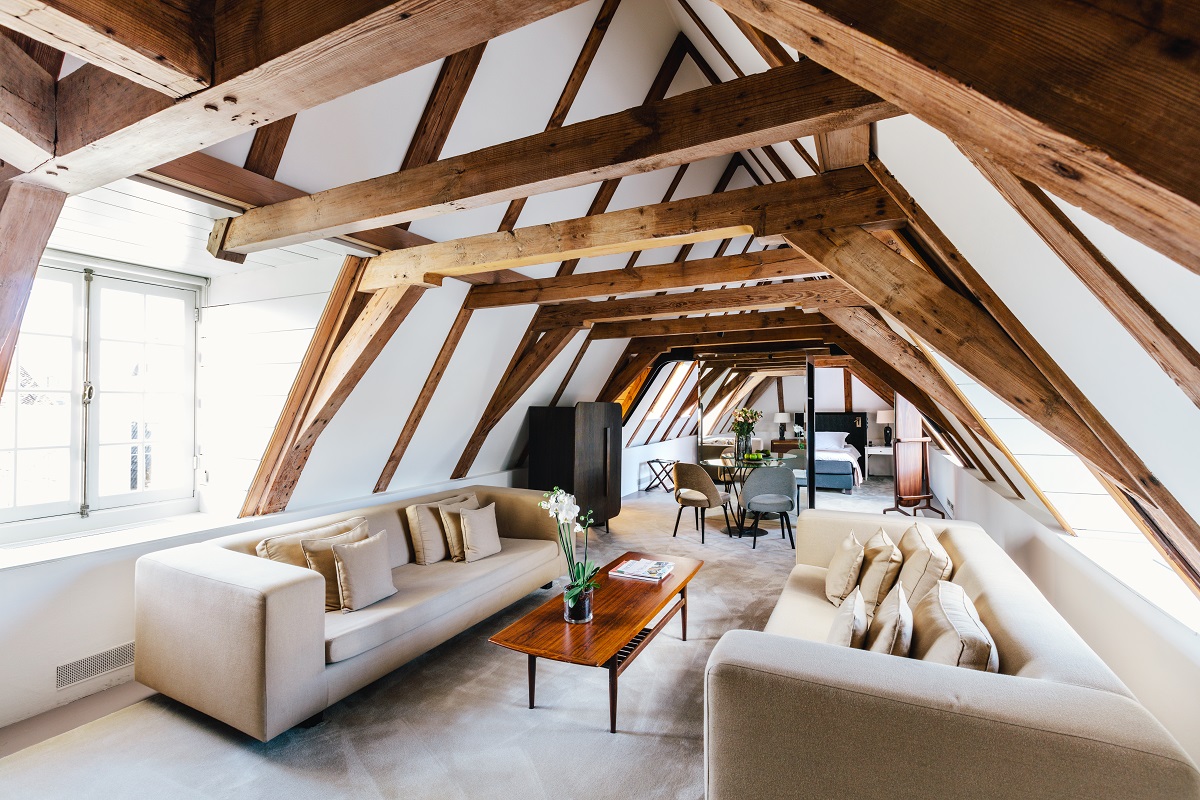 guest suite with couches and double bed under exposed wooden loft beams