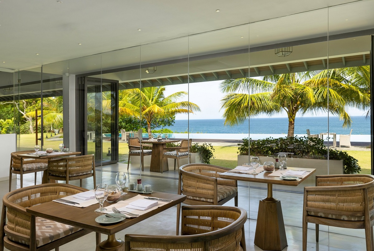 restaurant table and seating with view onto lawn, pool and sea