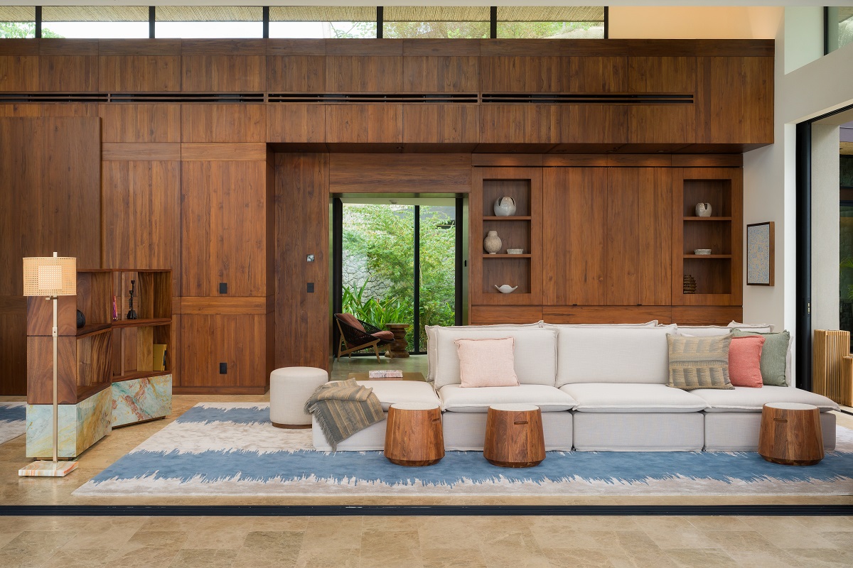double sided sofa and cream and wood furniture against wooden panelling and stone floors with woven carpet