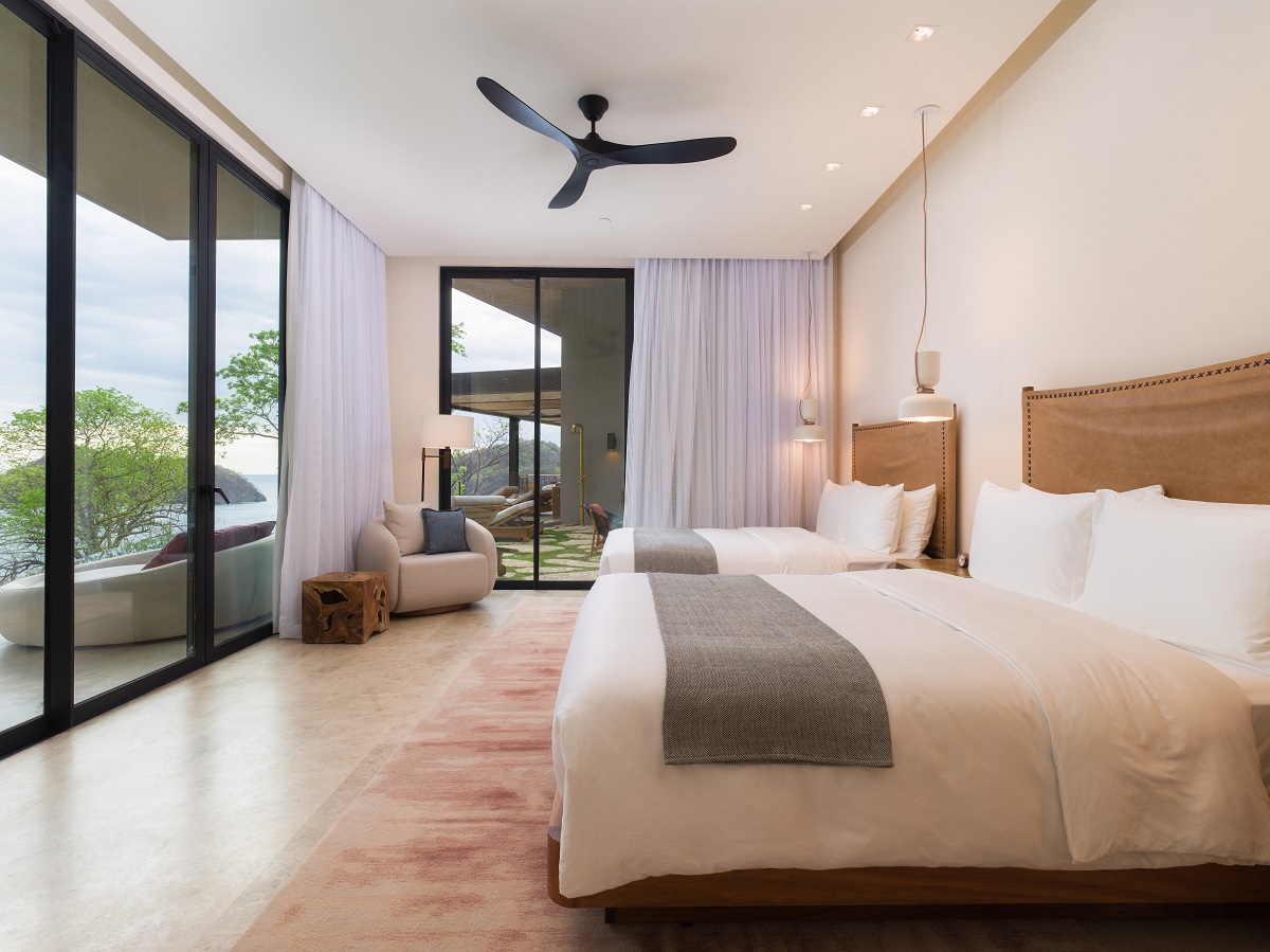 bedroom with bed facing floor to ceiling windows with ocean view