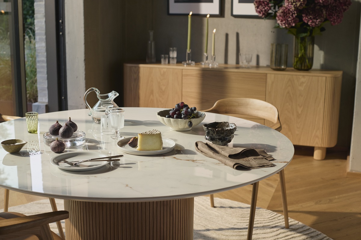 round BoConcept dining table with central wooden base and ceramic surface top
