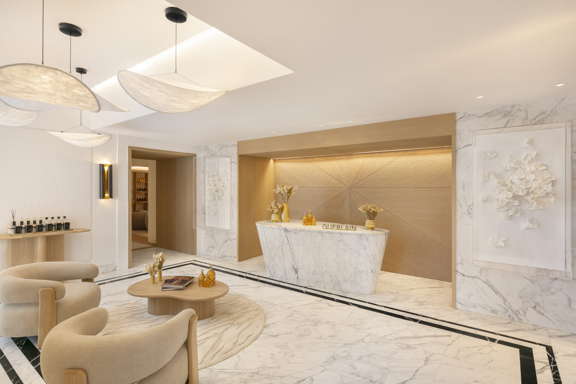 Reception of the Spa Metropole by Guerlain. Gold alcove surrounds desk while white marble floors and walls flood the space.