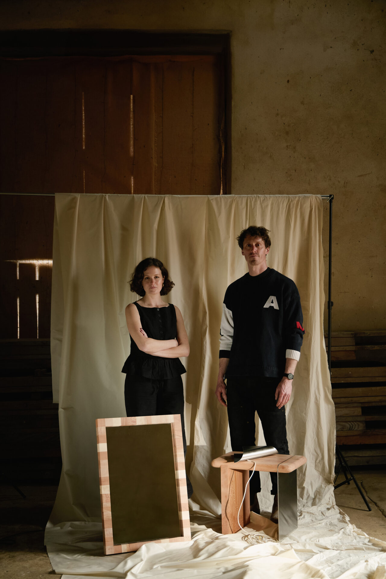 Tabitha Isobel and Dom Callaghan standing on white sheet with mirror, side table and wall lamp Ferro collection
