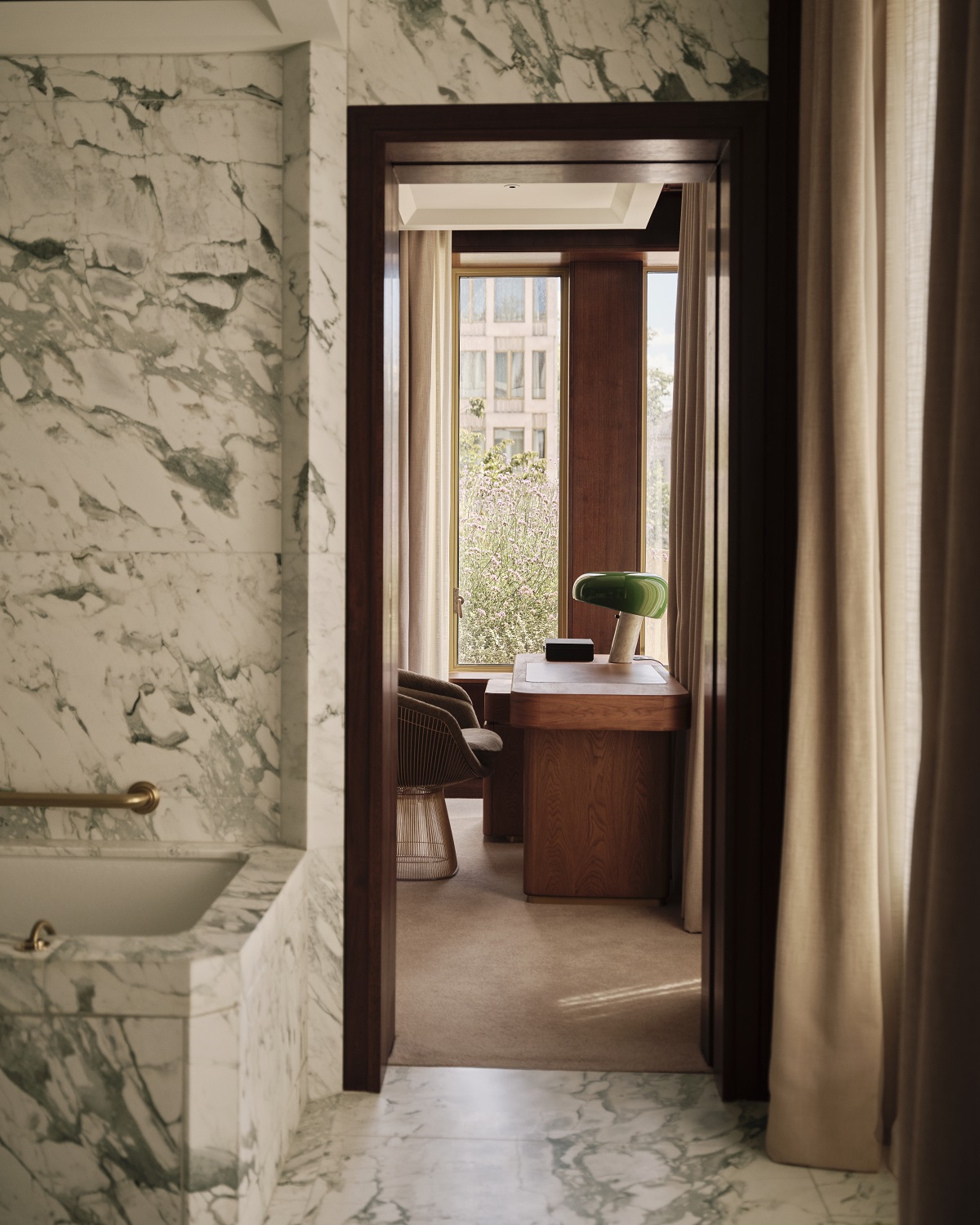 view from marble bathroom into suite with desk in The Chancery Rosewood