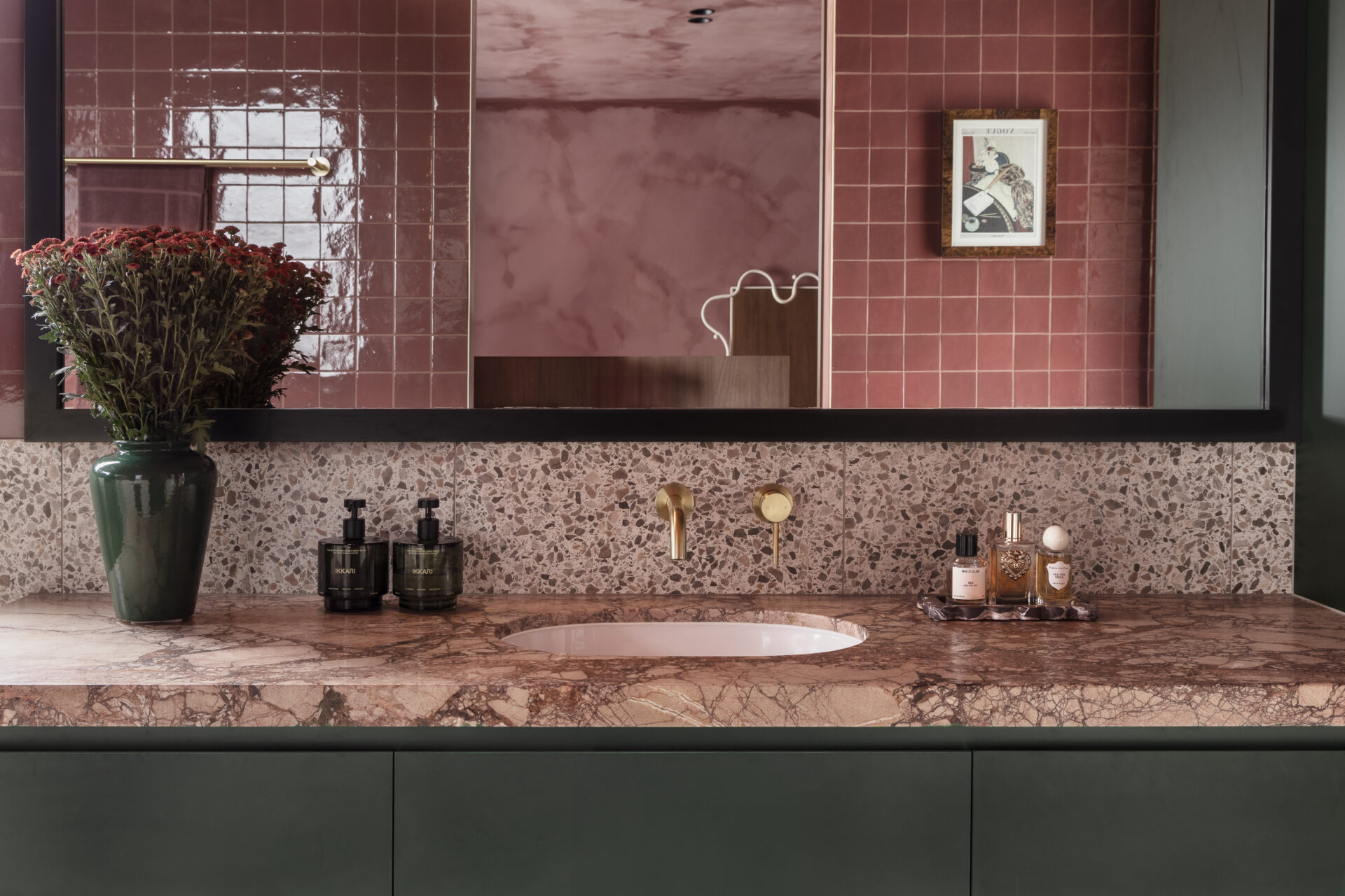 Red/pink stone bathroom with dark green walls and brass tap by ABI Interiors