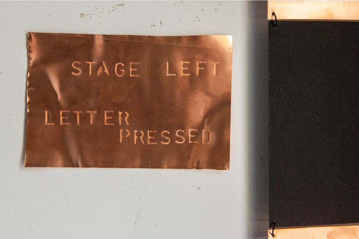 Copper square imprinted with lettering stating 'Stage Left Letter Pressed'