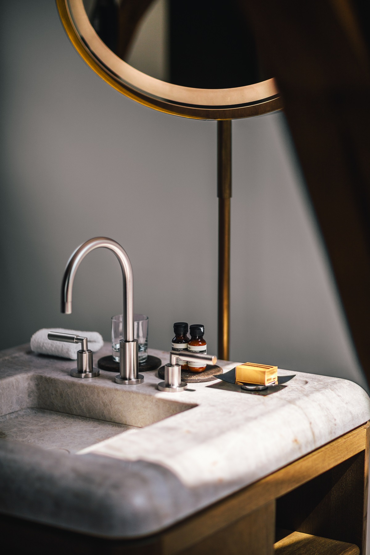 wood and marble vanity detail with round mirror in the Loft Suite