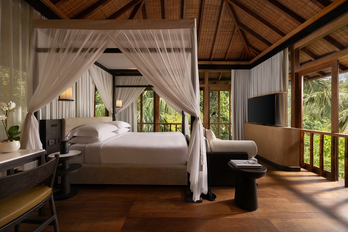 four poster bed in tropical setting with white draped fabric under pitched wooden roof of Wanakasa Residence Terrace Suite Bedroom