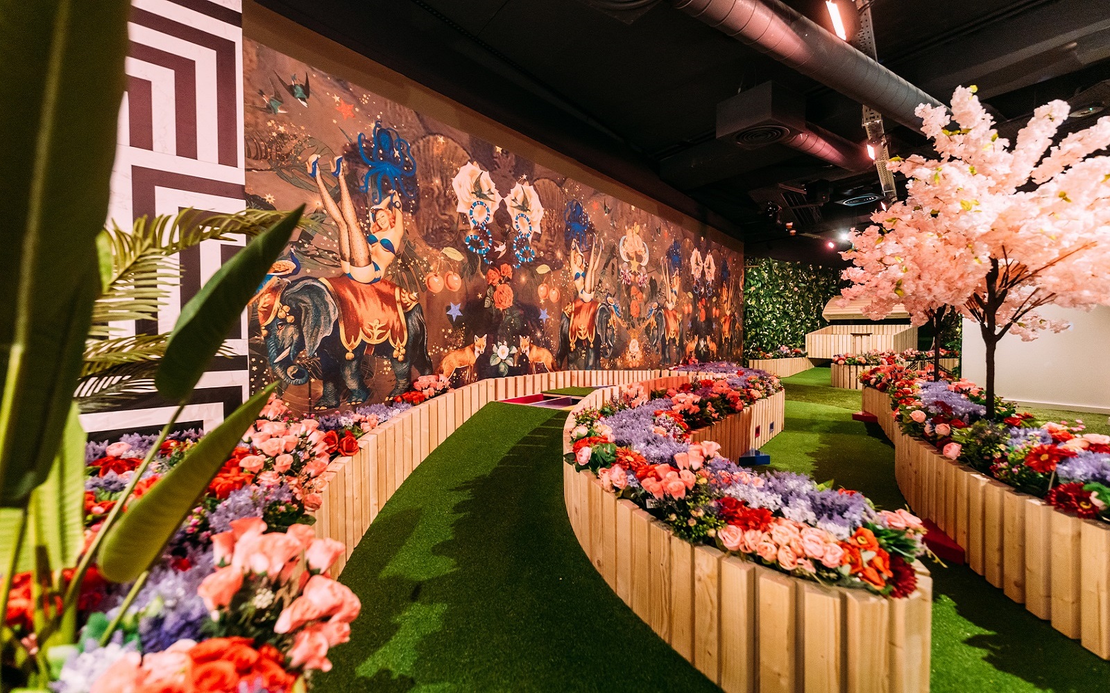 entrance ramp to game venue with a green path lined with fake flowers and bright patterned wall coverings from Newmor