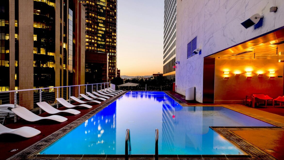 hotel swimming pool with view through highrise buildings to sunset