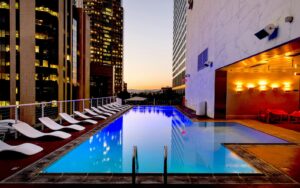 hotel swimming pool with view through highrise buildings to sunset