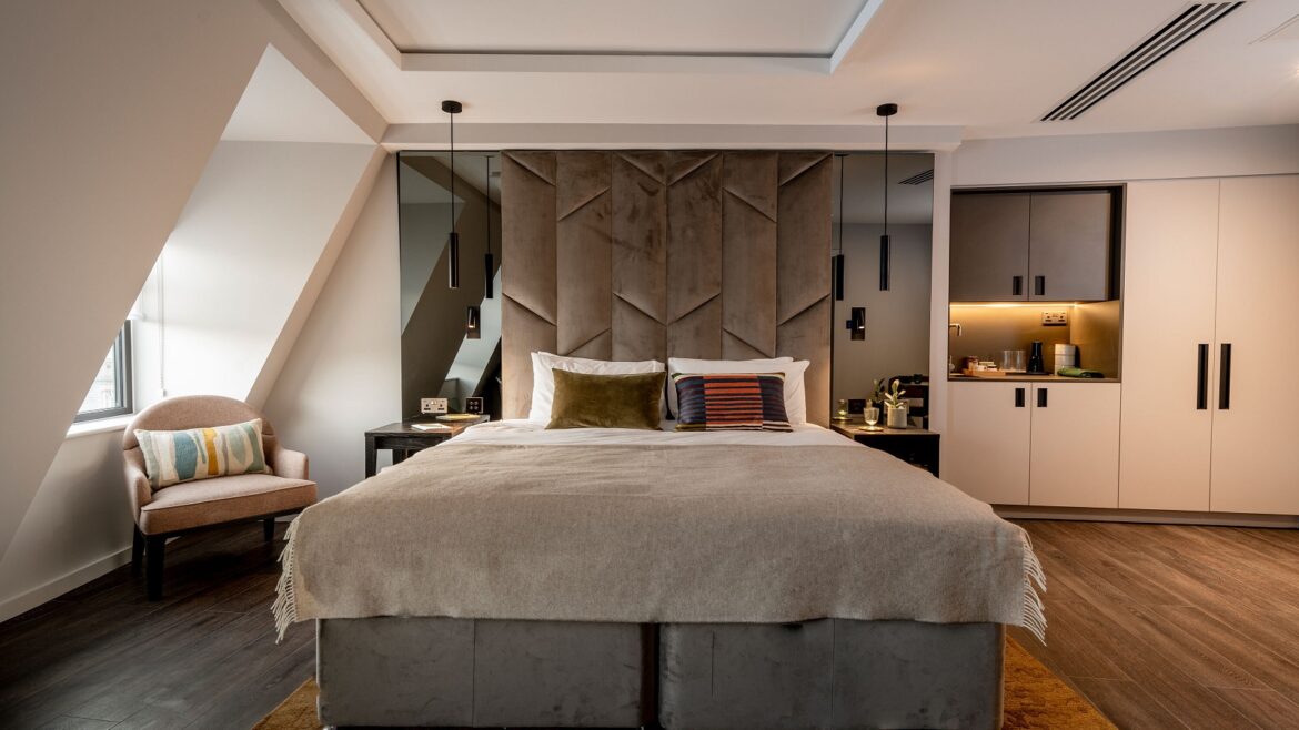 grey bed with white linen on wood floor in aparthotel suite Adina The Hobson