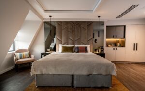 grey bed with white linen on wood floor in aparthotel suite Adina The Hobson