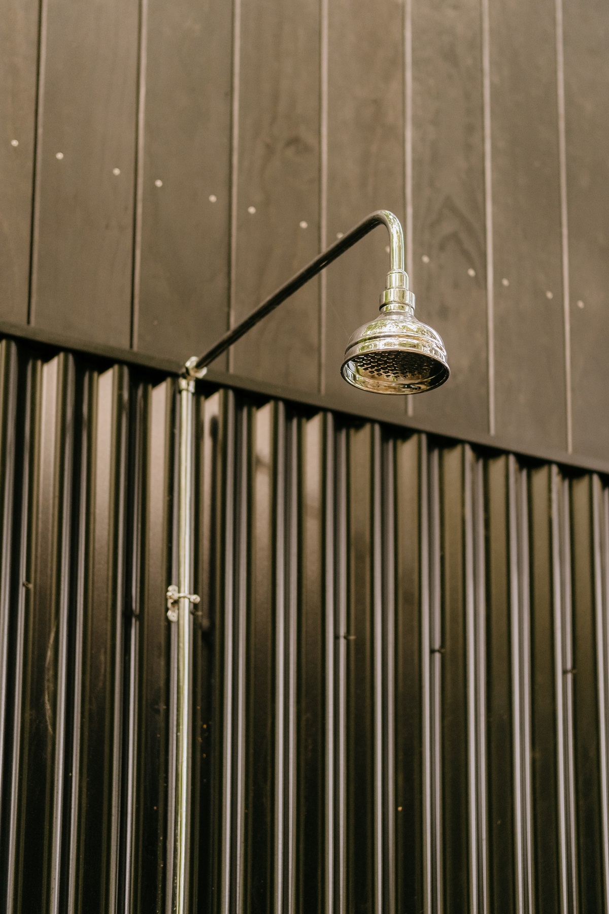 outdoor shower against black corrugated metal cladding