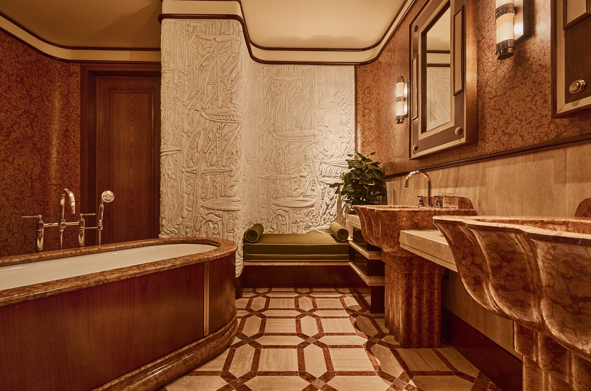 bathroom in the Obelisco Suite La Minerva with sculpted marble relief on the wall and Rosso Verano marble bath