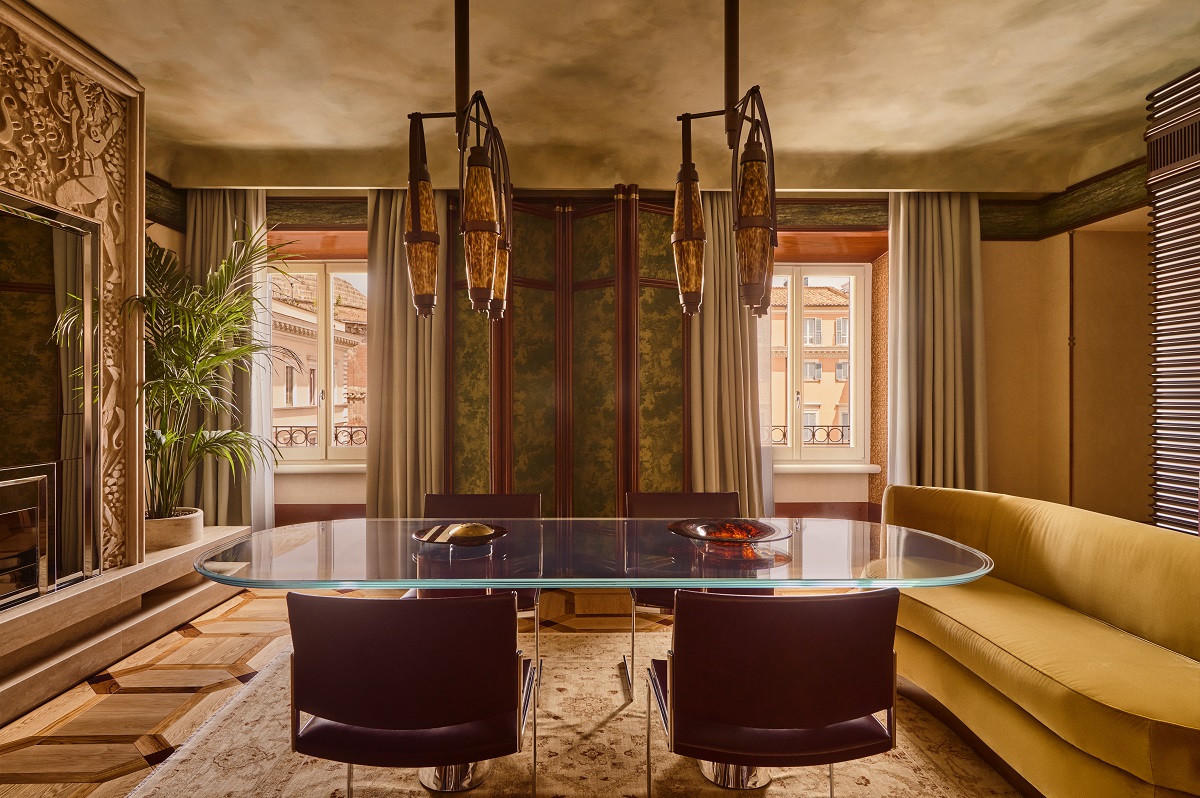glass topped dining table on wooden base with bespoke lighting, sculpted wall and curved sofa in Orient Express suite