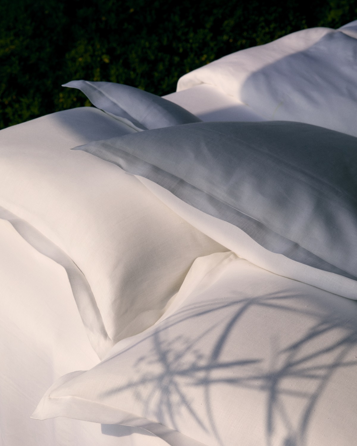 detail of white Frette bed linen with shadows of leaves
