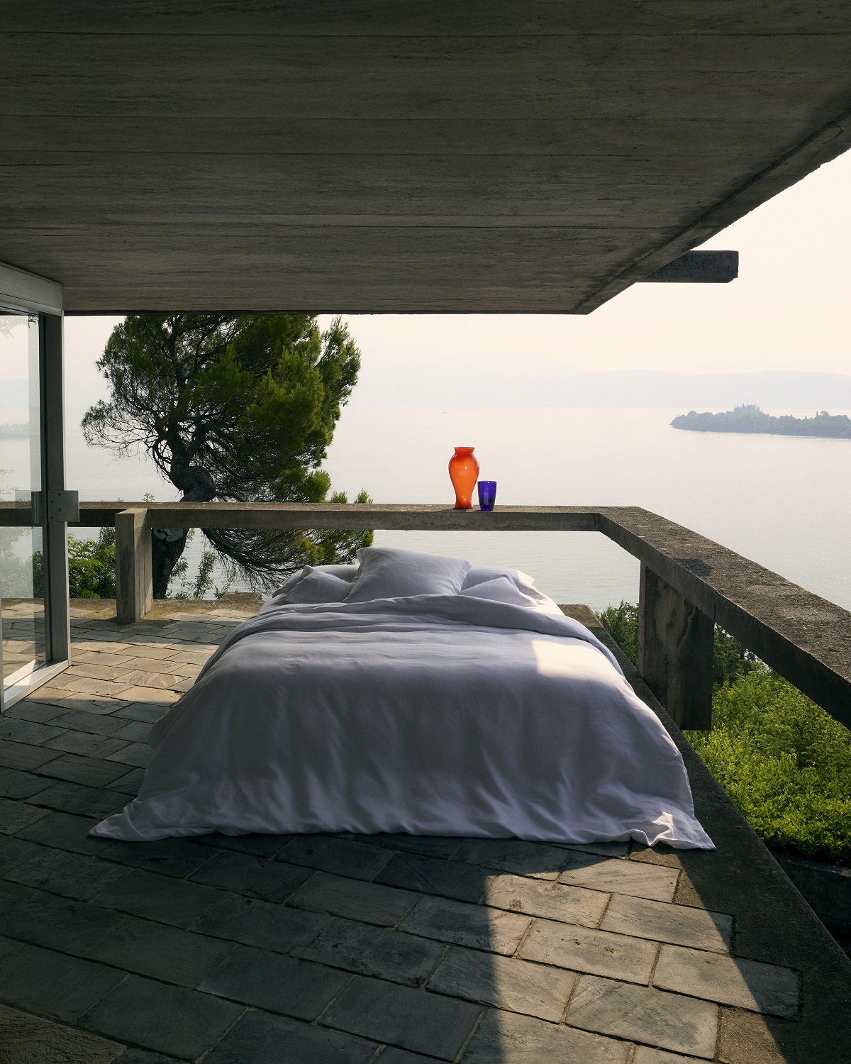 bed on terrace overlooking a lake with Frette bed linen