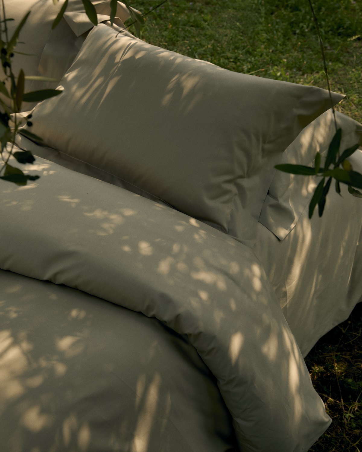 bed made up with Frette linen surrounded by olive trees