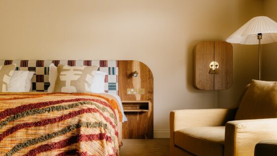 striped woven throw on bed with hand crafted cushions and wooden headboard