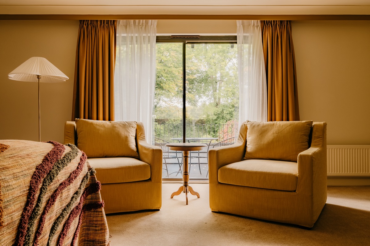 two armchairs in front of glass door leading on to terrace and lake