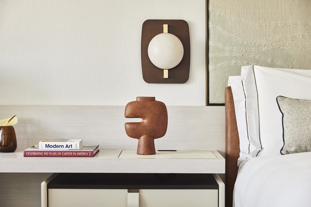 books, ceramic vase and textile headboard detail in guestroom