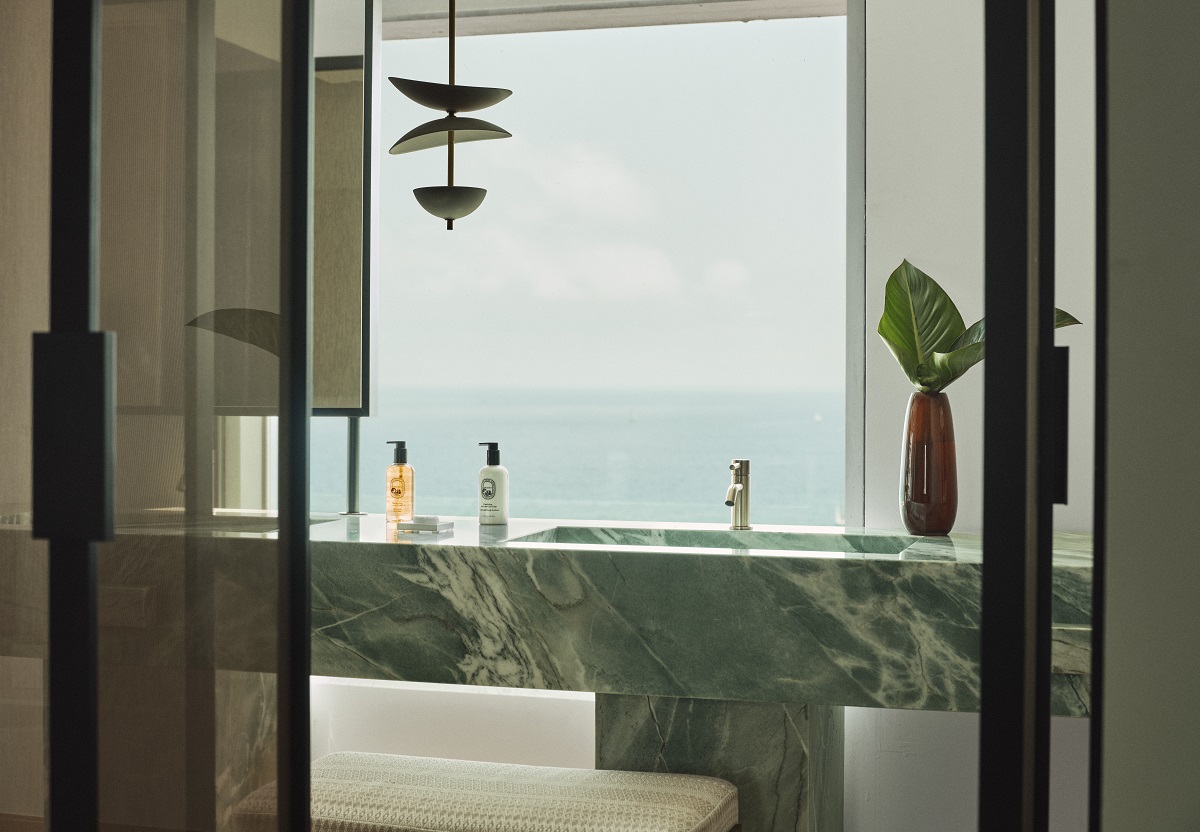 marble vanity in Hotel Arts Barcelona with pendant light framed by window and seaview