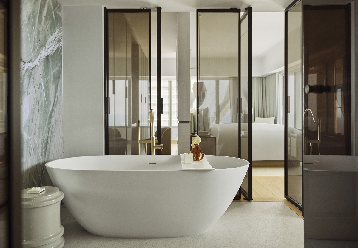 freestanding bath surrounded by glass doors and marble walls