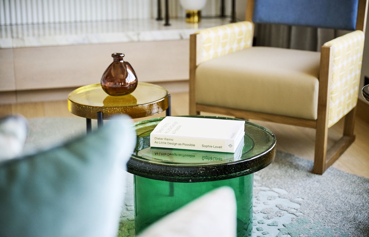 blue rug under green glass table with sand coloured seating in Hotel Arts Barcelona