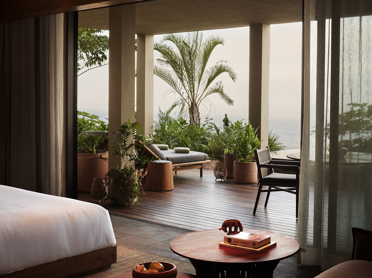 guestroom in Rosewood hotel leading on to terrace with palm tree and mountain view