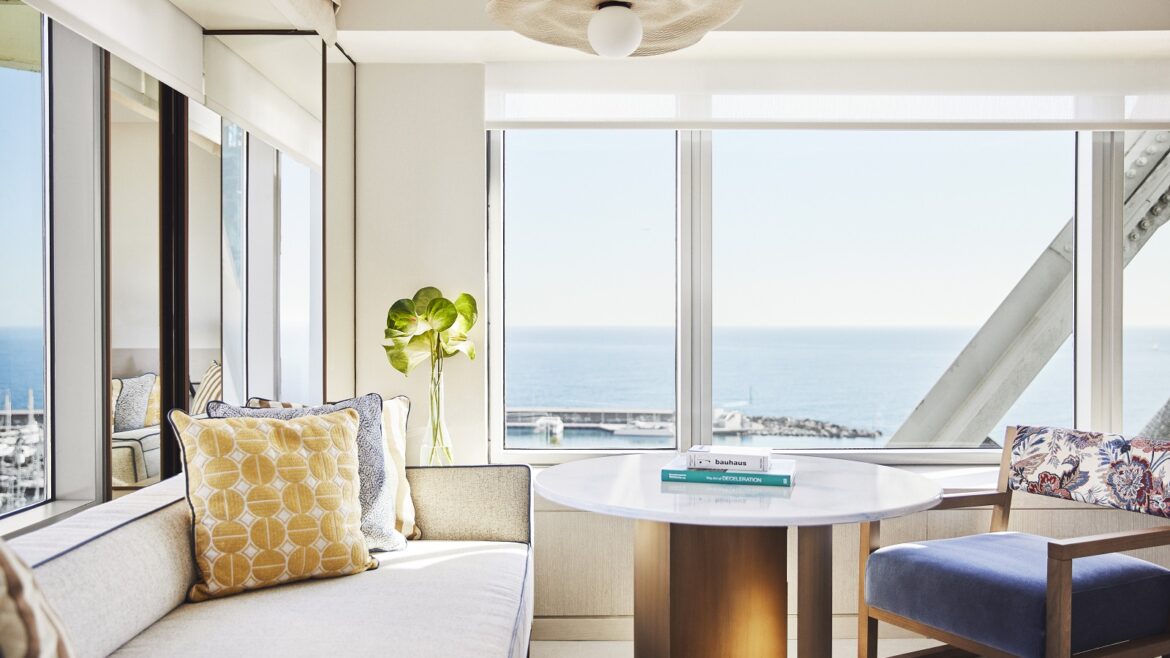guestroom in Hotel Arts Barcelona with cream couch next to window with sea view