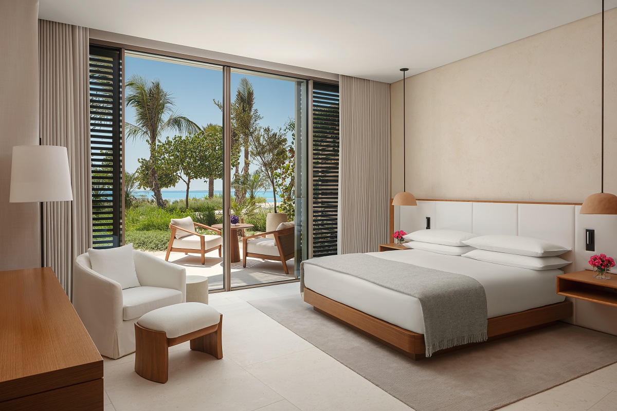 guestroom in EDITION with glass doors opening on to private terrace and palm trees