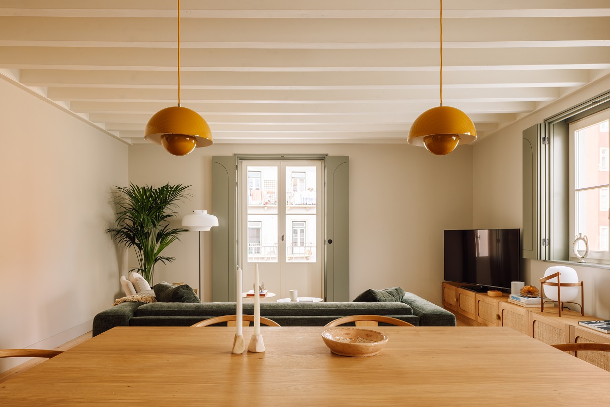 wooden dining table, mustard pendant lights and green couch