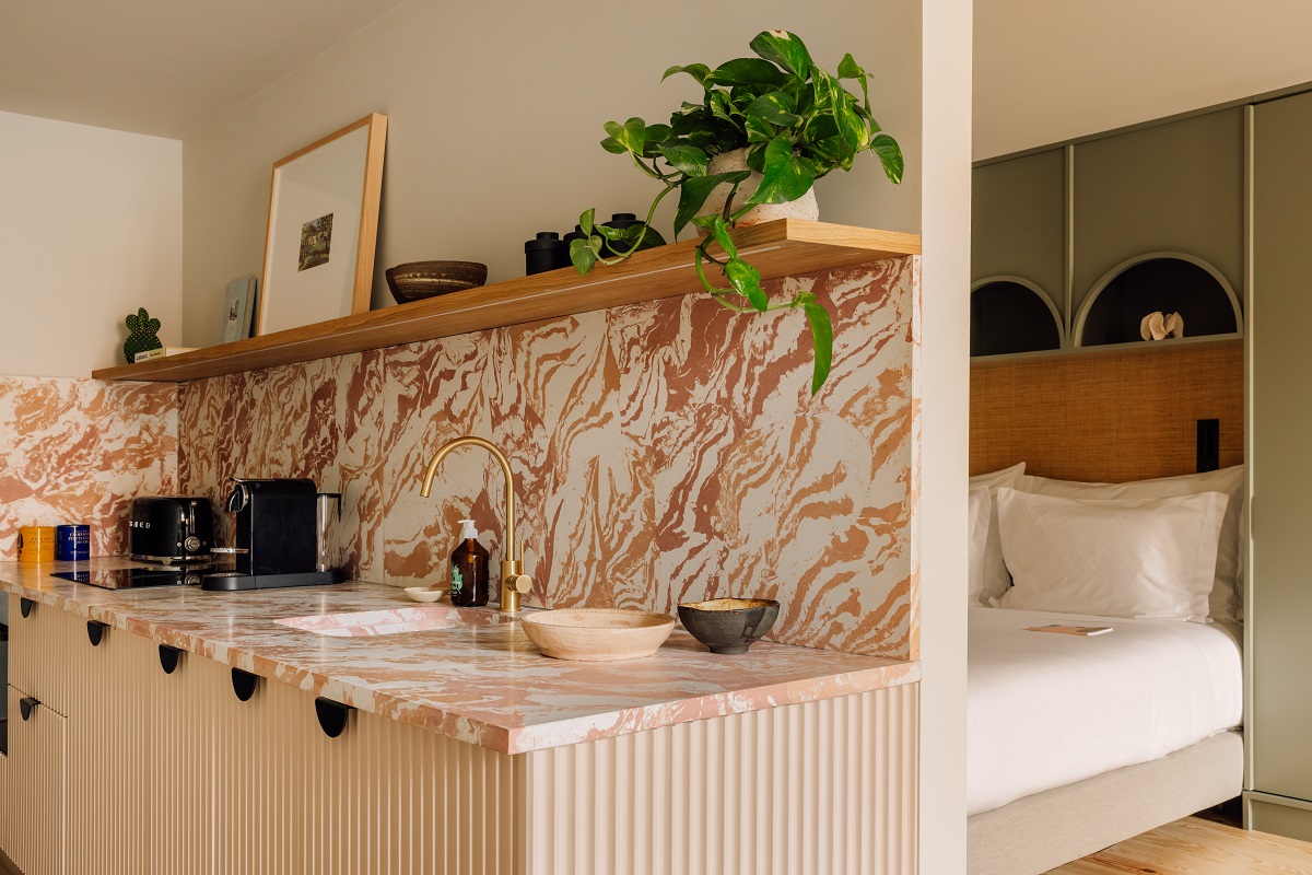 kitchen with marbled brown splashback backing on to bedroom