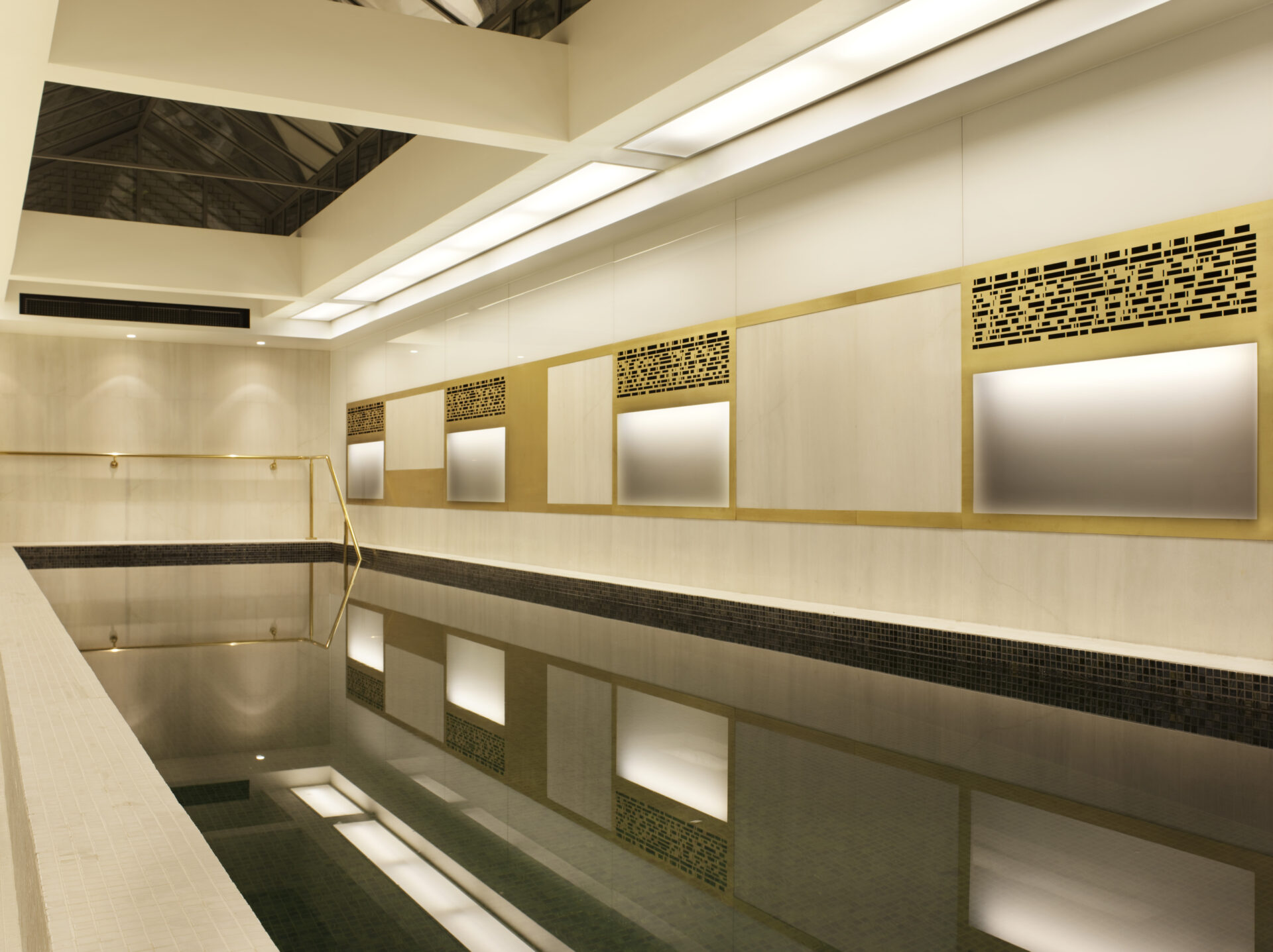 Indoor pool at Town Hall Hotel Bethnal Green. Pale stone and brass filigree sheets provide the decor