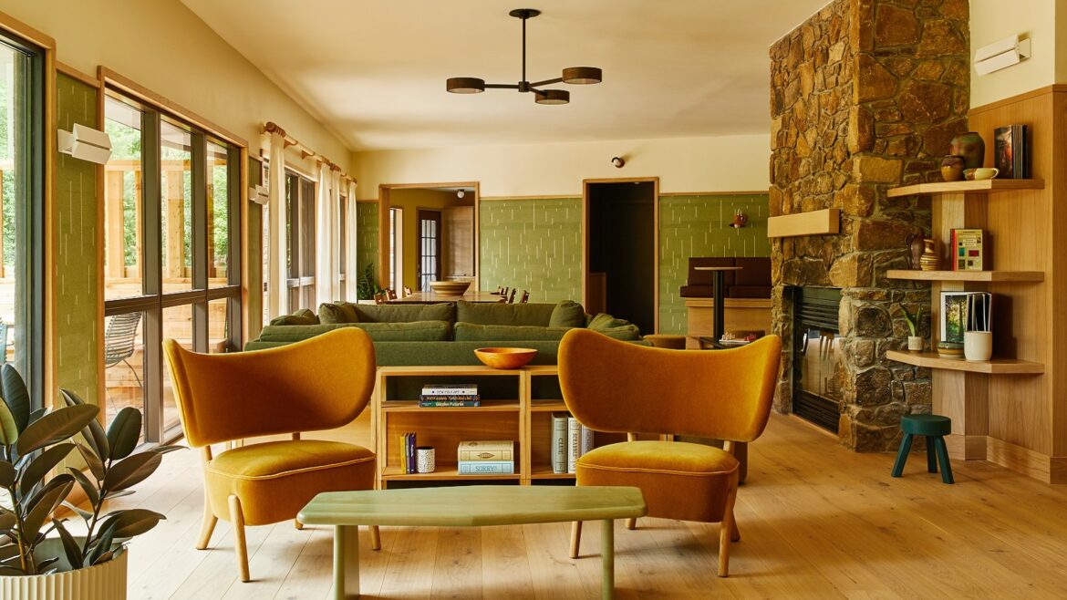 ochre chairs and olive green walls with stone fireplace in lounge of Trailborn Highlands hotel