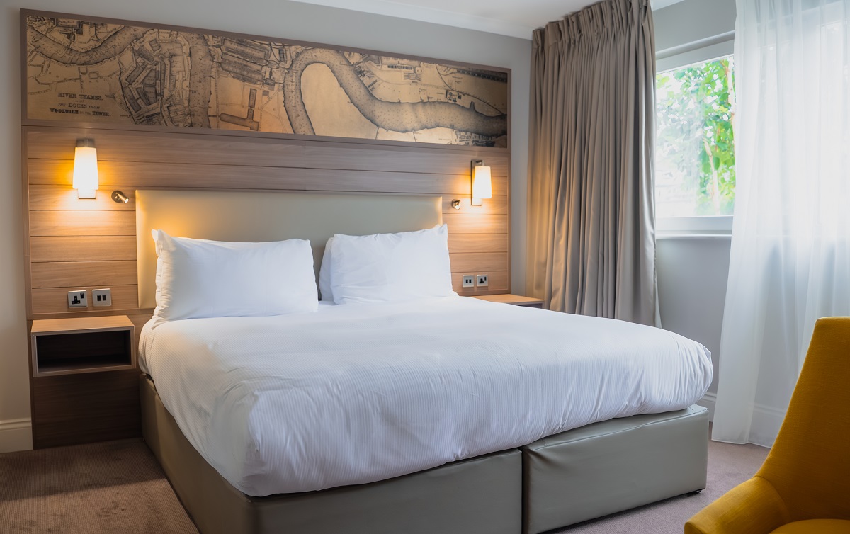 double bed with vintage map of london wallpaper behind in ao hostels london docklands