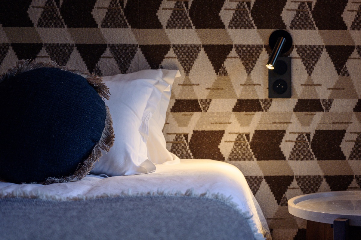 chevron wallpaper, behind bed detail with woolen throw and textured pillows